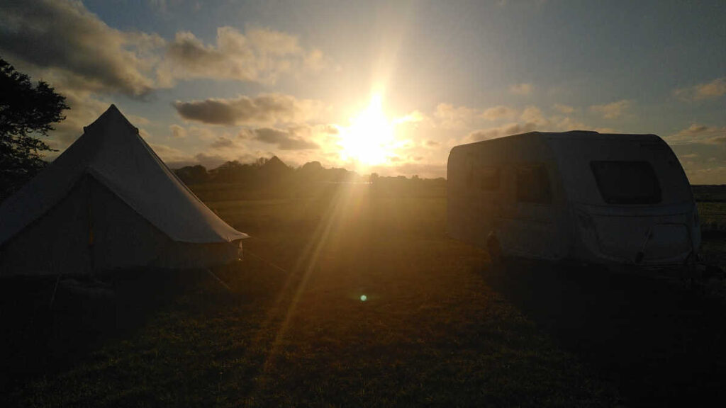 een tent en caravan op camping de Texelaar met zonsondergang